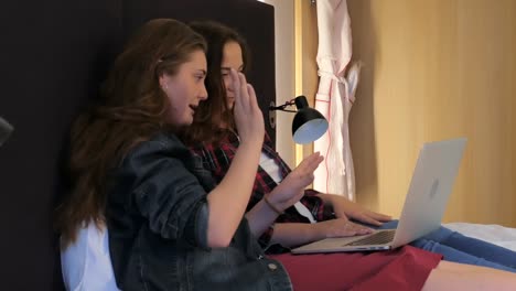 Two-attractive-young-women-in-bed-at-home-with-laptop.-Friendship-or-female-couple-concept