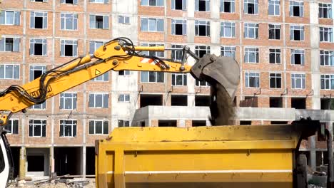 4K-view-of-excavator-bucket-pours-earth-into-the-back-of-a-truck