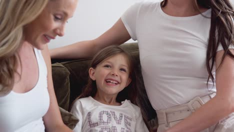 Mismo-sexo-pareja-femenina-leyendo-libro-con-su-hija-en-casa-juntos