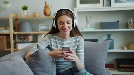 Beautiful-young-woman-is-listening-to-music-with-headphones-using-smartphone