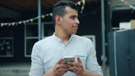 Portrait-of-handsome-mixed-race-man-using-smartphone-touching-screen-outside