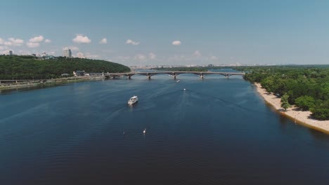 White-Cruise-Ship-Floats-Along-River-near-Beautiful-Modern-Bridge.