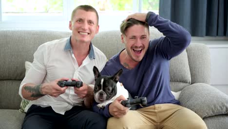 Gay-couple-relaxing-on-couch-with-dog-playing-games.-Dog-licking-face.