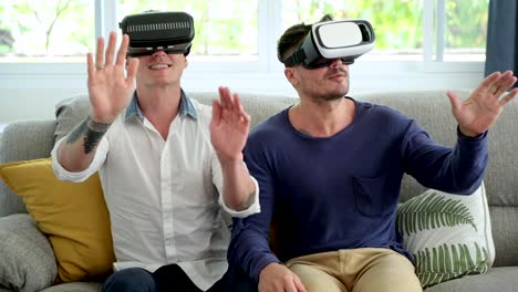 Schwules-Paar-entspannen-auf-der-Couch-mit-Virtual-Reality-Gerät.-Browsing-herum.