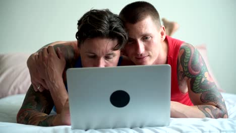 Pareja-gay-en-la-cama-usando-computadora-portátil.-Concéntrese-en-la-computadora.