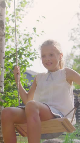 Joyous-Vater-schiebt-Swings-mit-seiner-süßen-kleinen-Tochter-auf-sie.-Glückliche-Familie-verbringt-Zeit-zusammen-einen-sonnigen-Sommertag-im-Idyllischen-Hinterhof.-Videomaterial-mit-vertikaler-Bildschirmausrichtung