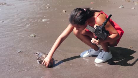 Una-vlogger-hembra-encontró-un-pez-muerto-en-la-orilla-del-mar-al-filmar-video.