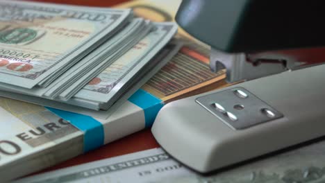 The-stapler-fastens-the-dollar-and-euro-notes-with-iron-clips.-Stapler-with-paper-clips-on-the-background-of-banknotes.-Counterfeit-money