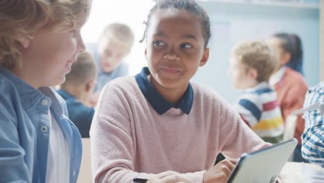 In-der-Grundschule:-Klasse-intelligenter-Kleiner-Kinder-arbeitet-als-Team-mit-Tablet-Computern,-um-Windkraftanlagen-zu-programmieren.-Klassenzimmer-mit-Kindern-Lernen-über-umweltfreundliche-Formen-erneuerbarer-Energie