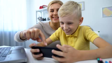 Mother-and-little-son-playing-together-new-game-on-smartphone,-leisure-time,-app