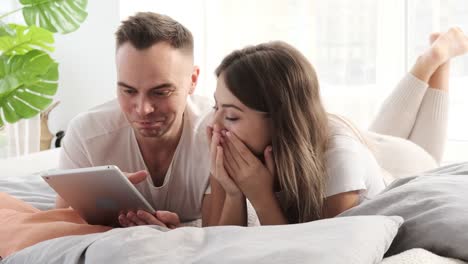 Couple-using-digital-tablet-in-bed