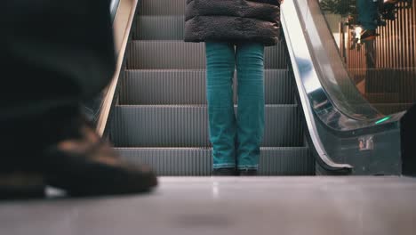 Piernas-de-personas-moviéndose-en-un-ascensor-de-escaleras-mecánicas-en-el-centro-comercial.-Pies-de-comprador-en-Escalera-Saltadora-en-el-Centro-Comercial