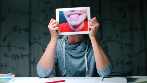 A-man-holds-a-tablet-in-his-hands,-on-the-tablet-screen-a-close-up-of-his-lips