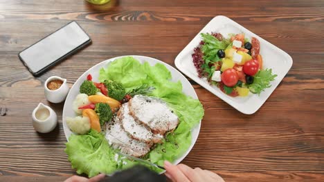 Manos-femeninas-sosteniendo-tenedor-y-cuchillo-comiendo-carne-de-pollo-con-ensalada-de-verduras.-Cámara-4k-Dragon-RED