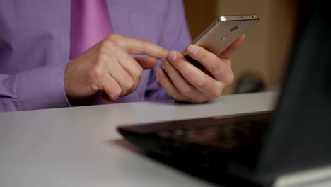 Un-hombre-de-negocios-con-camisa-y-corbata-morada-usa-un-teléfono-inteligente.-Lectura-de-noticias,-compras-en-línea,-visualización-de-redes-sociales.