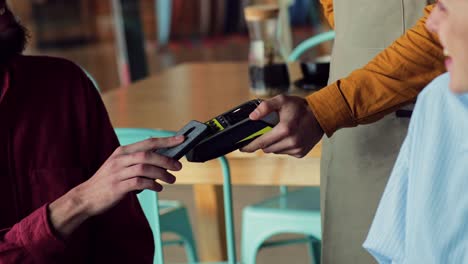 Close-up-man-paying-bill-with-contactless-smartphone-at-restaurant