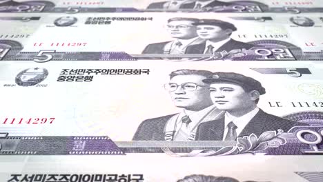 Banknoten-von-fünf-Won-von-Nordkorea-rollen,-Bargeld,-Schleife