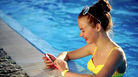 Young-woman-in-a-swimsuit-examines-photos-on-a-mobile-phone-for-social-networks