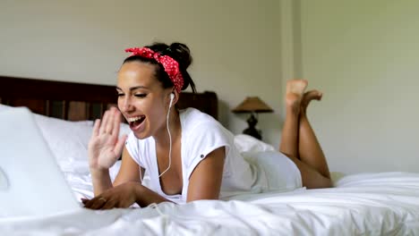 Joven-usando-de-la-computadora-portátil-al-tener-Video-Chat-llamar-hermosa-chica-hablando-acostado-en-cama-en-dormitorio-por-la-mañana