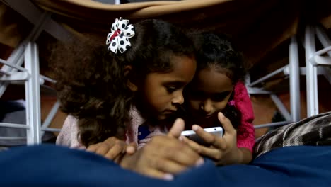 Dos-sonrientes-niños-viendo-fotos-graciosas-en-teléfono