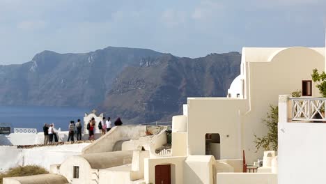 Group-of-tourist-standing-on-observation-deck-with-sea-at-back,-Santorini-island