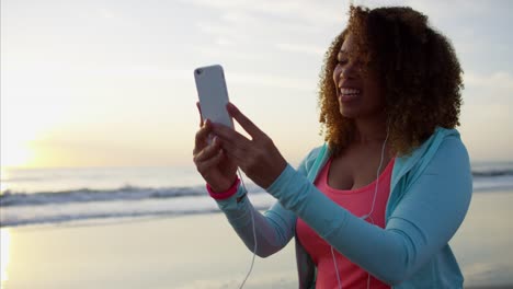 Ethnische-weiblich-zu-Fuß-am-Strand-mit-Smartphone