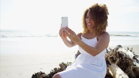 African-American-female-sitting-on-driftwood-by-ocean