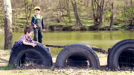 Two-kids-playing-together-jumping-and-climbing-on-old-tires