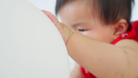 Cute-asian-little-baby-girl-having-fun-to-try-to-catch-and-play-with-balloon-in-slow-motion-shot