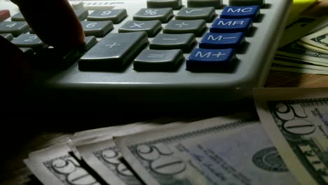 Man-using-calculator-for-business-calculations.-Close-up-of-hand,-money-and-calculator.