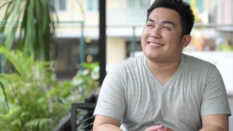 Young-handsome-overweight-Asian-man-relaxing-at-the-coffee-shop