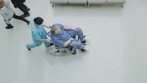 High-Angle-Shot-In-der-Krankenhaus-Lobby-des-medizinischen-Personals-drängen-Patienten-in-Rollstühlen,-Ärzte-und-Patienten-arbeiten-und-zu-Fuß.-Neues,-sauberes-Krankenhaus.