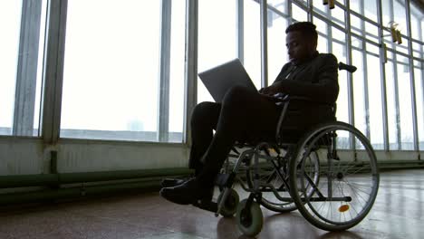 Businessman-in-Wheelchair-Working-before-Panoramic-Windows