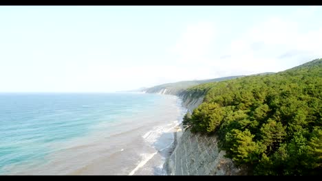 Aerial-photography,-rocky-coast-of-the-sea.-Green-forest-on-the-mountain.