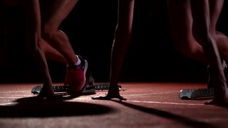 Three-sports-girl-athletes-at-night-on-the-treadmill-start-for-the-race-at-the-sprint-distance-from-the-sitting-position