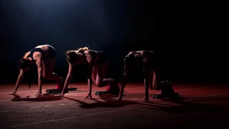 Three-girls-in-black-clothes-are-in-the-starting-pads-to-start-the-race-in-the-competition