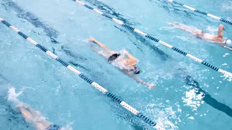 Top-view-four-professional-swimmer-floating-on-track-in-swimming-pool-performing-crawl-style