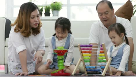 Happy-asian-family-with-two-daughters-playing-at-home.-Family-sitting-on-floor-and-playing-together.