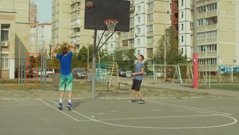 Two-teenage-friends-practicing-basketball-skills