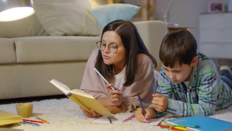 Mamá-y-niño-acostado-en-el-piso-en-casa-y-hacer-la-tarea