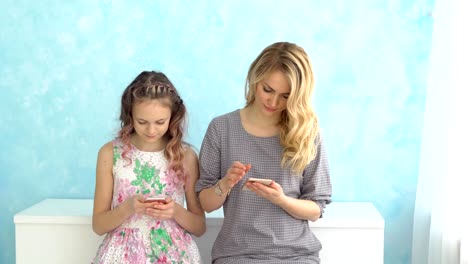 Mother-and-daughter-are-sitting-next-to-each-other-looking-in-their-phones-and-do-not-talk.