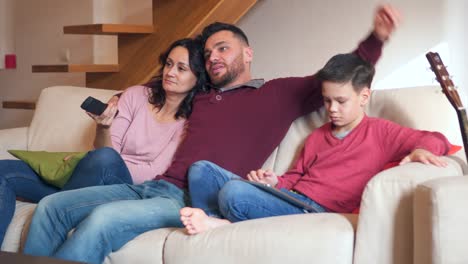 Family-watching-tv-and-using-digital-tablet-at-home