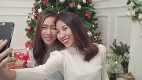 Gruppe-von-fröhlich-glücklich-junge-Asiatin-mit-Smartphone-Selfie-mit-Weihnachtsbaum-dekorieren-Sie-ihr-Wohnzimmer-zu-Hause-in-Christmas-Festival.-Lifestyle-Frauen-feiern-Weihnachten-und-Neujahr-Konzept.