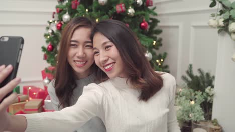 Group-of-cheerful-happy-young-Asian-woman-using-smartphone-selfie-with-christmas-tree-decorate-her-living-room-at-home-in-Christmas-Festival.-Lifestyle-women-celebrate-Christmas-and-New-year-concept.