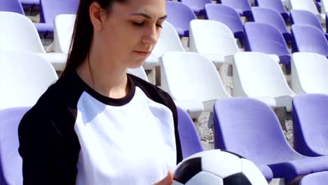 Young-woman-footballer-seating-with-football-soccer-ball-on-stadium,-4k