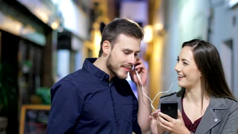 Couple-sharing-music-in-the-night-in-the-street