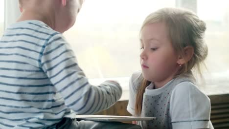 Kleiner-Junge-und-seine-Schwester-spielen-auf-Tablet