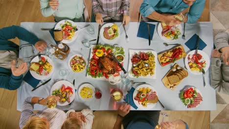 Gran-familia-y-fiesta-de-amigos-en-casa,-grupo-diverso-de-personas-se-reunieron-en-la-mesa,-brindar-en-un-brindis.-Gente-comiendo,-bebiendo-y-divirtiéndose-en-la-sala-de-estar.-Arriba-hacia-abajo-por-encima-de-tiro.