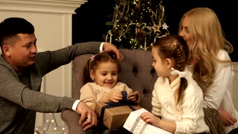 Los-padres-y-dos-niños-divirtiéndose-y-jugando-juntos-cerca-de-árbol-de-Navidad-en-el-interior