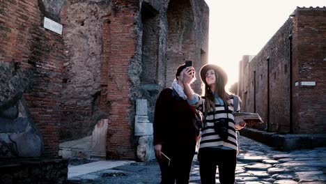 Happy-Caucasian-mother-and-daughter-take-a-selfie-photo-while-exploring-old-antique-streets-of-Pompeii,-Italy-together.